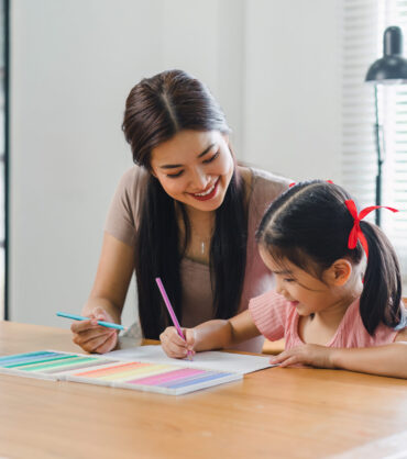mother teaching daughter and helping her with homework at home. education, family and homework concept