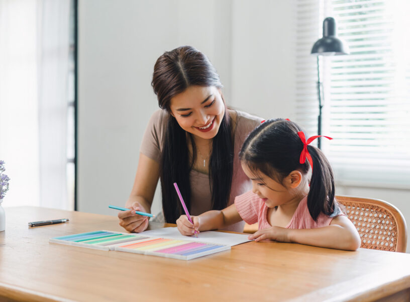 mother teaching daughter and helping her with homework at home. education, family and homework concept