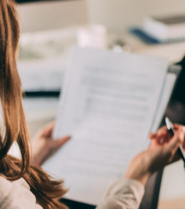 Close up of businesswoman working on paperwork and writing new business plans in the office.