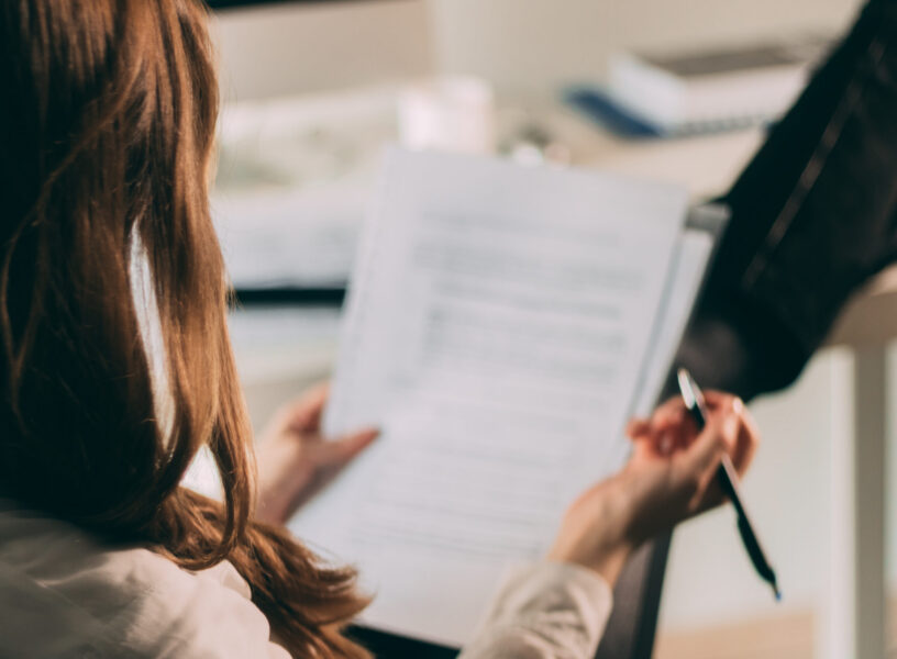 Close up of businesswoman analyzing business reports. Close up of businesswoman working on paperwork and writing new business plans in the office.